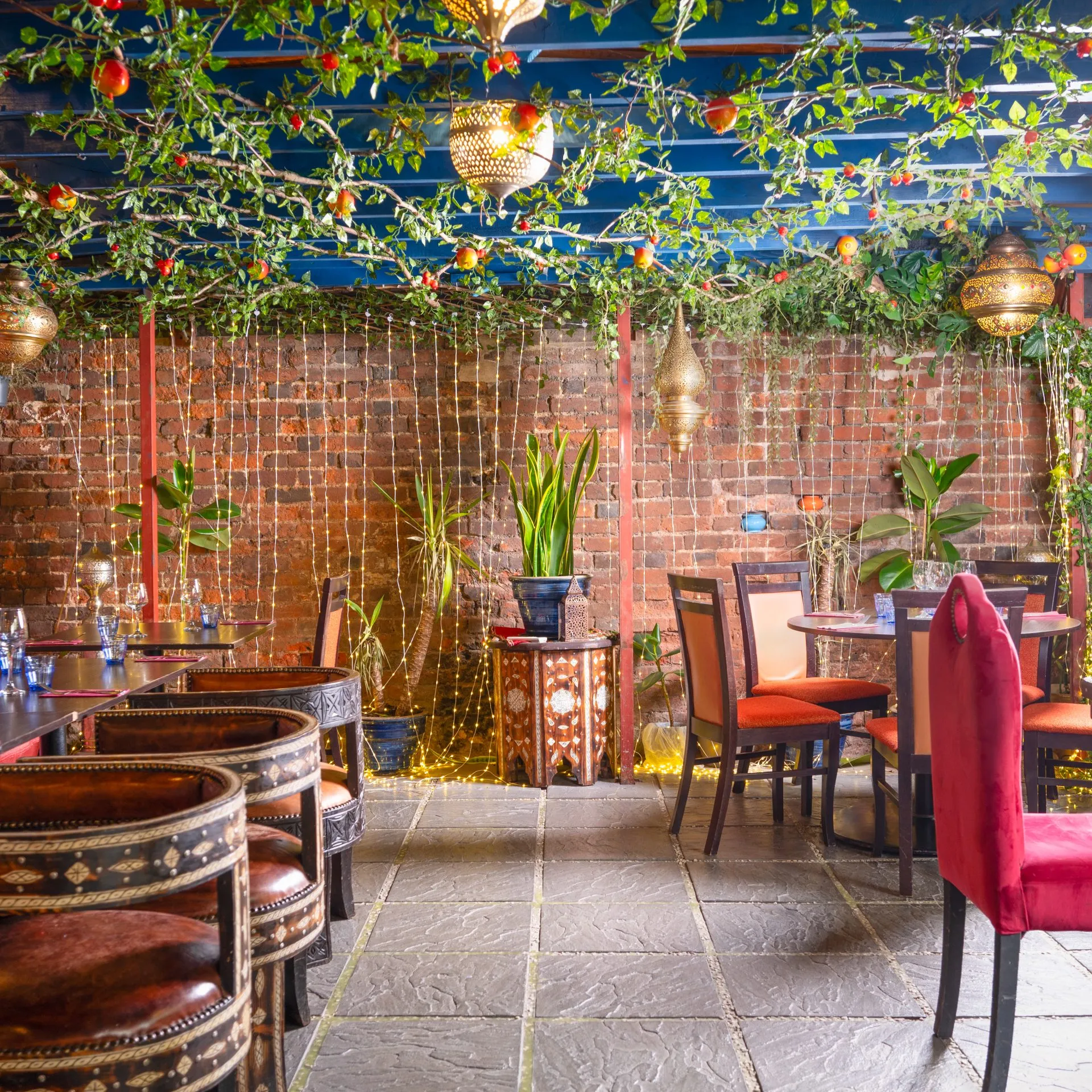 The Pomegranate Garden private dining room at Al Farid, wrapped in windows with hanging foliage and pomegranates